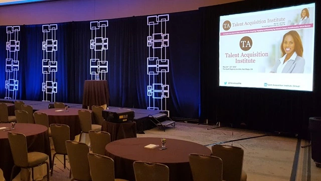 Large-scale ballroom production featuring three-screen brand integration and modular scenic drapes for an enterprise event set design case study.