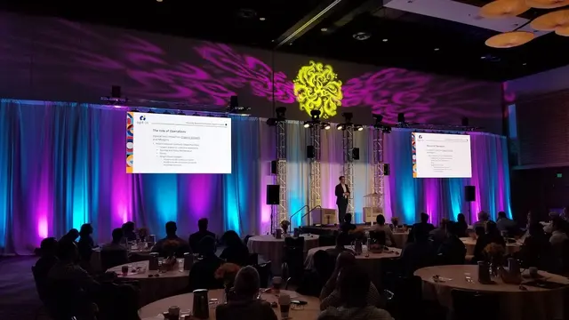 Enterprise event lighting in San Diego featuring a keynote stage, intelligent lighting design, presentation screens, and a corporate conference audience.